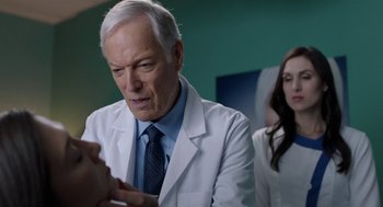 Movie still from “Nightmare Cinema” (2018), directed by Alejandro Brugués – An older man wearing a lab coat and a tie; Close Up shot, Over the shoulder angle