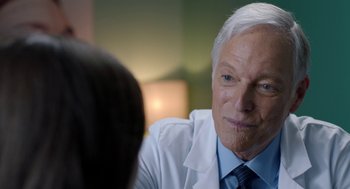 Movie still from “Nightmare Cinema” (2018), directed by Alejandro Brugués – An older man wearing a white lab coat; Close Up shot, Over the shoulder angle