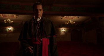 Movie still from “Nightmare Cinema” (2018), directed by Alejandro Brugués – A man in a black and red robe standing in a theater; Medium shot, Low angle