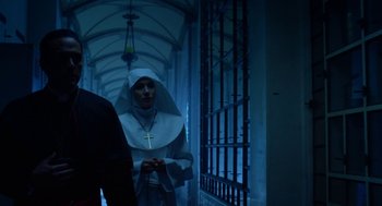 Movie still from “Nightmare Cinema” (2018), directed by Alejandro Brugués – A woman in a nun's outfit standing in a dark hallway; Medium shot, Low angle