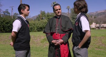 Movie still from “Nightmare Cinema” (2018), directed by Alejandro Brugués – A man in a black and red outfit standing next to two other men; Medium shot, Over the shoulder angle