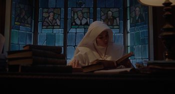Movie still from “Nightmare Cinema” (2018), directed by Alejandro Brugués – A nun reading a book in front of a stained glass window; Medium shot, Low angle