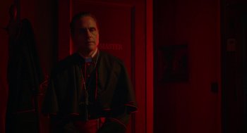 Movie still from “Nightmare Cinema” (2018), directed by Alejandro Brugués – A man standing in front of a door in a dark room; Medium shot, Low angle