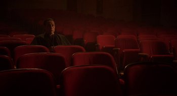 Movie still from “Nightmare Cinema” (2018), directed by Alejandro Brugués – A man sitting in a red chair in a movie theater; Wide shot, High angle