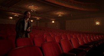 Movie still from “Nightmare Cinema” (2018), directed by Alejandro Brugués – A woman standing in an empty theater with red seats; Wide shot, High angle