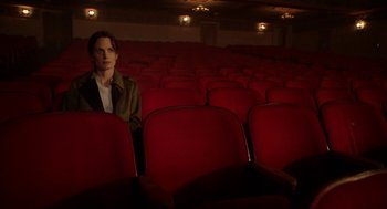Movie still from “Nightmare Cinema” (2018), directed by Alejandro Brugués – A man sitting in a red chair in an auditorium; Wide shot, High angle
