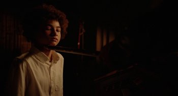 Movie still from “Nightmare Cinema” (2018), directed by Alejandro Brugués – A woman in a white shirt is standing in a dark room; Close Up shot, Over the shoulder angle