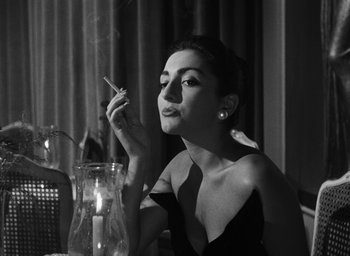 Movie still from “Nights of Cabiria” (1957), directed by Federico Fellini – A black and white photo of a woman smoking a cigarette; Close Up shot, Low angle