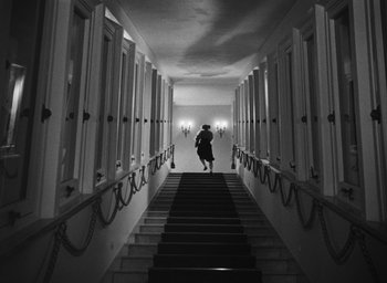 Movie still from “Nights of Cabiria” (1957), directed by Federico Fellini – A woman walking down a set of stairs in a building; Wide shot, Low angle