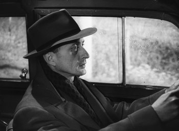 Movie still from “Nights of Cabiria” (1957), directed by Federico Fellini – A man in a hat driving a car in the rain; Close Up shot, Low angle