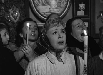 Movie still from “Nights of Cabiria” (1957), directed by Federico Fellini – A group of people holding candles in a room; Medium shot, High angle