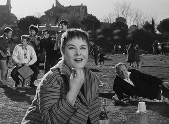 Movie still from “Nights of Cabiria” (1957), directed by Federico Fellini – An old black and white photo of a woman smiling; Medium shot, High angle