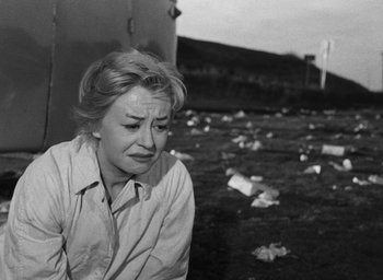 Movie still from “Nights of Cabiria” (1957), directed by Federico Fellini – An old photo of a woman sitting on the ground; Medium shot, High angle
