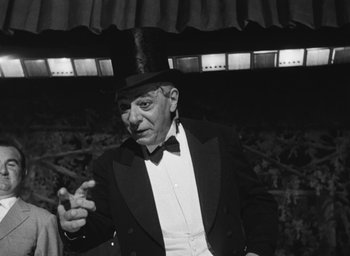 Movie still from “Nights of Cabiria” (1957), directed by Federico Fellini – An older man in a suit and hat is pointing; Medium shot, Low angle