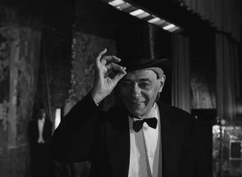 Movie still from “Nights of Cabiria” (1957), directed by Federico Fellini – An older man wearing a hat and a tuxedo; Close Up shot, Low angle