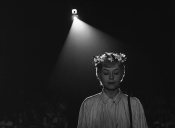 Movie still from “Nights of Cabiria” (1957), directed by Federico Fellini – A woman wearing a flower crown standing in front of a spotlight; Close Up shot, Low angle