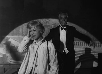 Movie still from “Nights of Cabiria” (1957), directed by Federico Fellini – A man and a boy are standing in front of a building; Medium shot, Low angle