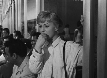 Movie still from “Nights of Cabiria” (1957), directed by Federico Fellini – A black - and - white photo of a woman holding her hand to her mouth; Medium shot, Over the shoulder angle