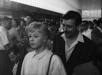 Movie still from “Nights of Cabiria” (1957), directed by Federico Fellini – A man and a woman are standing in a crowd of people; Medium shot, Over the shoulder angle