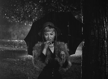 Movie still from “Nights of Cabiria” (1957), directed by Federico Fellini – A woman holding an umbrella while standing in the rain; Medium shot, Low angle