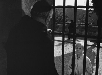 Movie still from “Nights of Cabiria” (1957), directed by Federico Fellini – A black and white photo of a man and a boy behind a fence; Medium shot, High angle