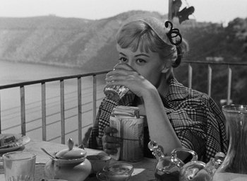 Movie still from “Nights of Cabiria” (1957), directed by Federico Fellini – A black and white photo of a woman drinking a beverage; Medium shot, High angle