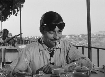 Movie still from “Nights of Cabiria” (1957), directed by Federico Fellini – A black and white photo of a man sitting at a table; Close Up shot, Over the shoulder angle