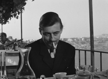 Movie still from “Nights of Cabiria” (1957), directed by Federico Fellini – A black and white photo of a man sitting at a table; Medium shot, Low angle