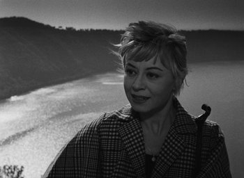 Movie still from “Nights of Cabiria” (1957), directed by Federico Fellini – A black - and - white photo of a woman holding a pipe in her mouth; Close Up shot, High angle