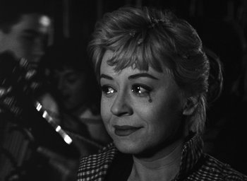 Movie still from “Nights of Cabiria” (1957), directed by Federico Fellini – A black and white photo of a woman with a sad look on her face; Close Up shot, Over the shoulder angle