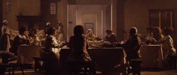 Movie still from “Nightwatching” (2007), directed by Peter Greenaway – A group of people sitting around a table eating food; Wide shot, High angle