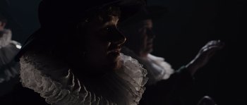 Movie still from “Nightwatching” (2007), directed by Peter Greenaway – A man with a beard wearing a white shirt and a black hat; Close Up shot, Over the shoulder angle
