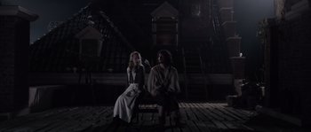 Movie still from “Nightwatching” (2007), directed by Peter Greenaway – Two people sitting on a bench in a dark room; Wide shot, High angle