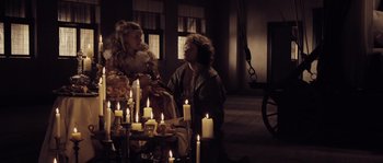 Movie still from “Nightwatching” (2007), directed by Peter Greenaway – A man and a woman sitting in front of candles; Wide shot, High angle