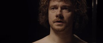 A person with curly hair and a beard