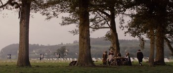 Movie still from “Nightwatching” (2007), directed by Peter Greenaway – A group of people sitting under a large tree in a field; Extreme Wide shot, High angle