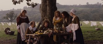 Movie still from “Nightwatching” (2007), directed by Peter Greenaway – A group of people sitting around a table with food on top of it; Wide shot, High angle
