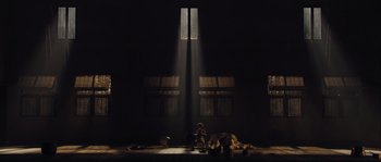 Movie still from “Nightwatching” (2007), directed by Peter Greenaway – A person sitting on a chair in front of a window in a dark room; Extreme Wide shot, Low angle