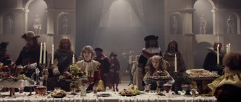 Movie still from “Nightwatching” (2007), directed by Peter Greenaway – A group of people standing around a table with food on it; Wide shot, High angle