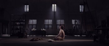 Movie still from “Nightwatching” (2007), directed by Peter Greenaway – A woman sitting on the ground in a room; Wide shot, High angle