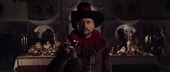 A man in a red and black outfit holding a wine goblet