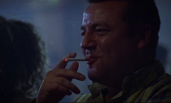 Movie still from “Nil by Mouth” (1997), directed by Gary Oldman – A person holding a cigarette in his mouth; Close Up shot, Low angle