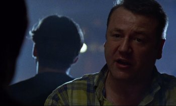 Movie still from “Nil by Mouth” (1997), directed by Gary Oldman – A person in a yellow and blue shirt; Close Up shot, Over the shoulder angle