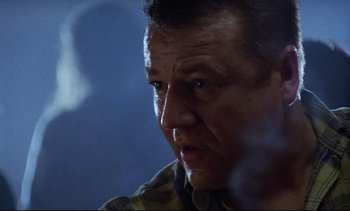 Movie still from “Nil by Mouth” (1997), directed by Gary Oldman – A man's face in the dark; Close Up shot, Low angle