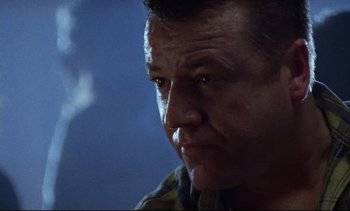 Movie still from “Nil by Mouth” (1997), directed by Gary Oldman – A man's face in a dark room; Close Up shot, Low angle