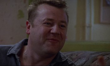 Movie still from “Nil by Mouth” (1997), directed by Gary Oldman – A person sitting on a couch; Close Up shot, Low angle