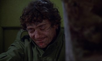 Movie still from “Nil by Mouth” (1997), directed by Gary Oldman – A man with a face tattoo is sitting in front of a tree; Close Up shot, Over the shoulder angle