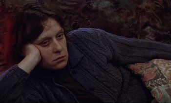 Movie still from “Nil by Mouth” (1997), directed by Gary Oldman – A person laying on the ground wearing a sweater; Close Up shot, High angle