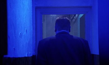 Movie still from “Nil by Mouth” (1997), directed by Gary Oldman – A man in a suit looking out of a window; Medium shot, Low angle