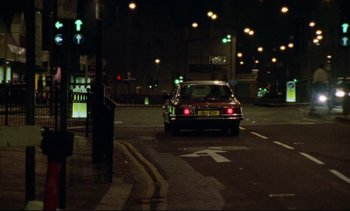 Movie still from “Nil by Mouth” (1997), directed by Gary Oldman – A car is stopped at a traffic light at night; Extreme Wide shot, Low angle